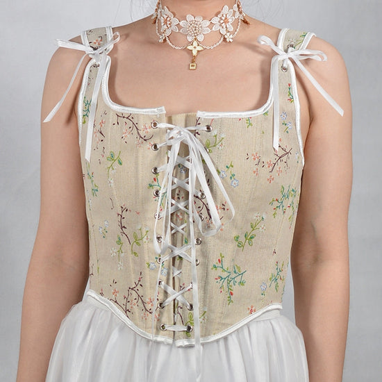 Vintage'owy gorsetowy top w beżowym kolorze z delikatnym kwiatowym wzorem i wiązanymi ramiączkami. Idealny do romantycznych stylizacji.
